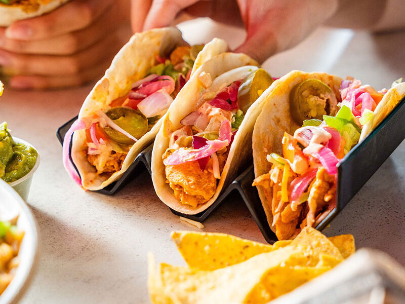 a person grabbing for one of three tacos